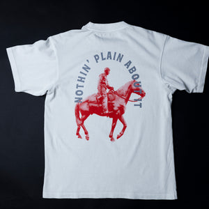 off-White short-sleeve T-shirt shown from the back against a black background, featuring a large red graphic of a cowboy riding a horse with the text 'NOTHIN' PLAIN ABOUT IT' in blue arched above.
